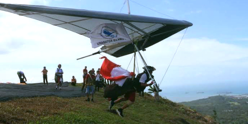 Aksi memukau atlet gantole saat lepas landas dari bukit, bagian dari Paragliding Accuracy Championship Kotabaru Hebat 2025.