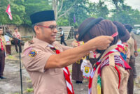 Wakil Bupati Kotabaru Syairi Mukhlis, S.Sos selaku Ka Pembina Kwarcab Gerakan Pramuka Kotabaru menyematkan tanda peserta kepada anggota Pramuka saat pembukaan Kemah Pasak Todak II di Pantai Gedambaan, Pulau Laut Sigam, Minggu (14/12/2025). (Foto:DiskominfoKtb) 