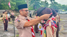 Wakil Bupati Kotabaru Syairi Mukhlis, S.Sos selaku Ka Pembina Kwarcab Gerakan Pramuka Kotabaru menyematkan tanda peserta kepada anggota Pramuka saat pembukaan Kemah Pasak Todak II di Pantai Gedambaan, Pulau Laut Sigam, Minggu (14/12/2025). (Foto:DiskominfoKtb) 