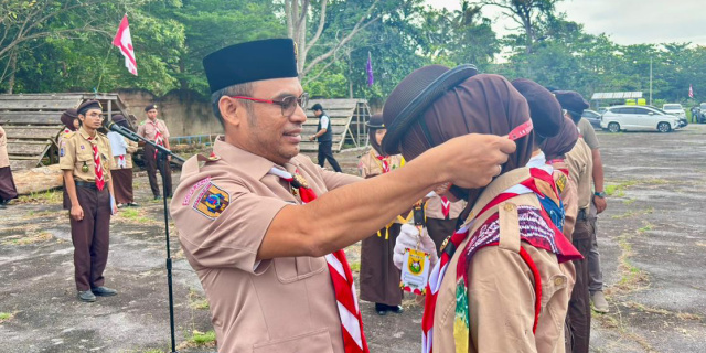 Wakil Bupati Kotabaru Syairi Mukhlis, S.Sos selaku Ka Pembina Kwarcab Gerakan Pramuka Kotabaru menyematkan tanda peserta kepada anggota Pramuka saat pembukaan Kemah Pasak Todak II di Pantai Gedambaan, Pulau Laut Sigam, Minggu (14/12/2025). (Foto:DiskominfoKtb) 